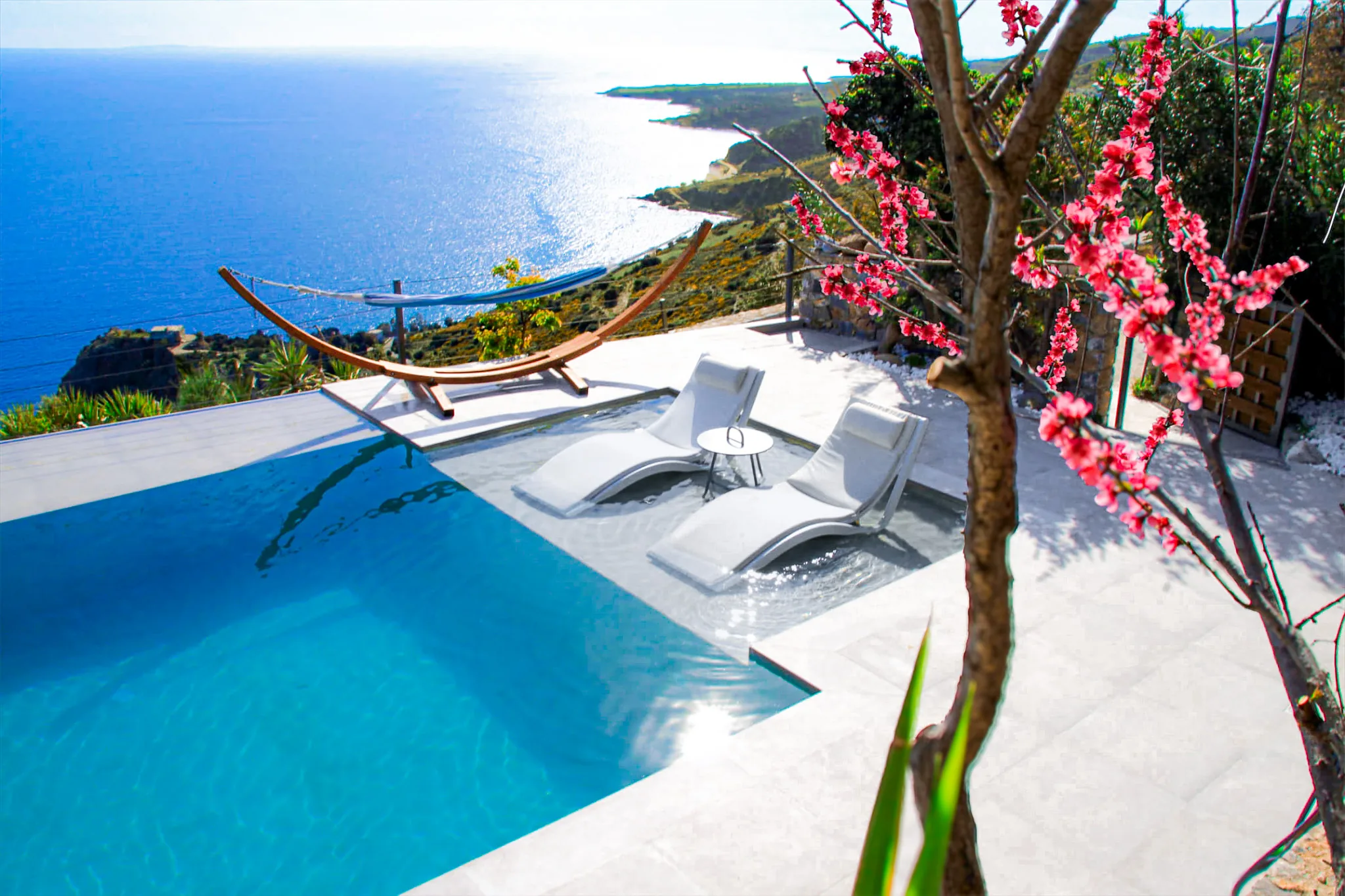 Pool, sunbeds and hammock above the sea